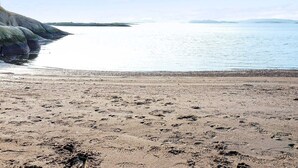 Una spiaggia con impronte e un litorale roccioso.