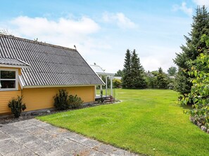 A residential property with a sloped roof, a covered porch, and a well-maintained lawn. - 4 Star Holiday Home in Dannemare (Dannemare)