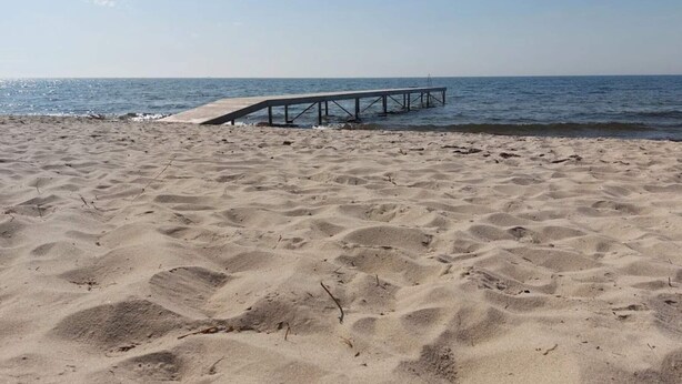 A sandy beach with a wooden pier extending into the water. - 4 Star Holiday Home in Dannemare (Dannemare)