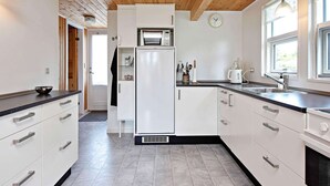A modern kitchen with white cabinets, a built-in microwave, and a sink. - 4 Star Holiday Home in Dannemare (Dannemare)