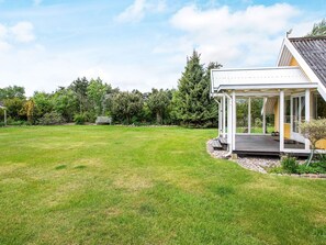 A spacious lawn with a wooden deck and a covered outdoor seating area. - 4 Star Holiday Home in Dannemare (Dannemare)