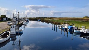 A calm water body with boats docked on the left and a grassy field on the right. - 4 Star Holiday Home in Dannemare (Dannemare)