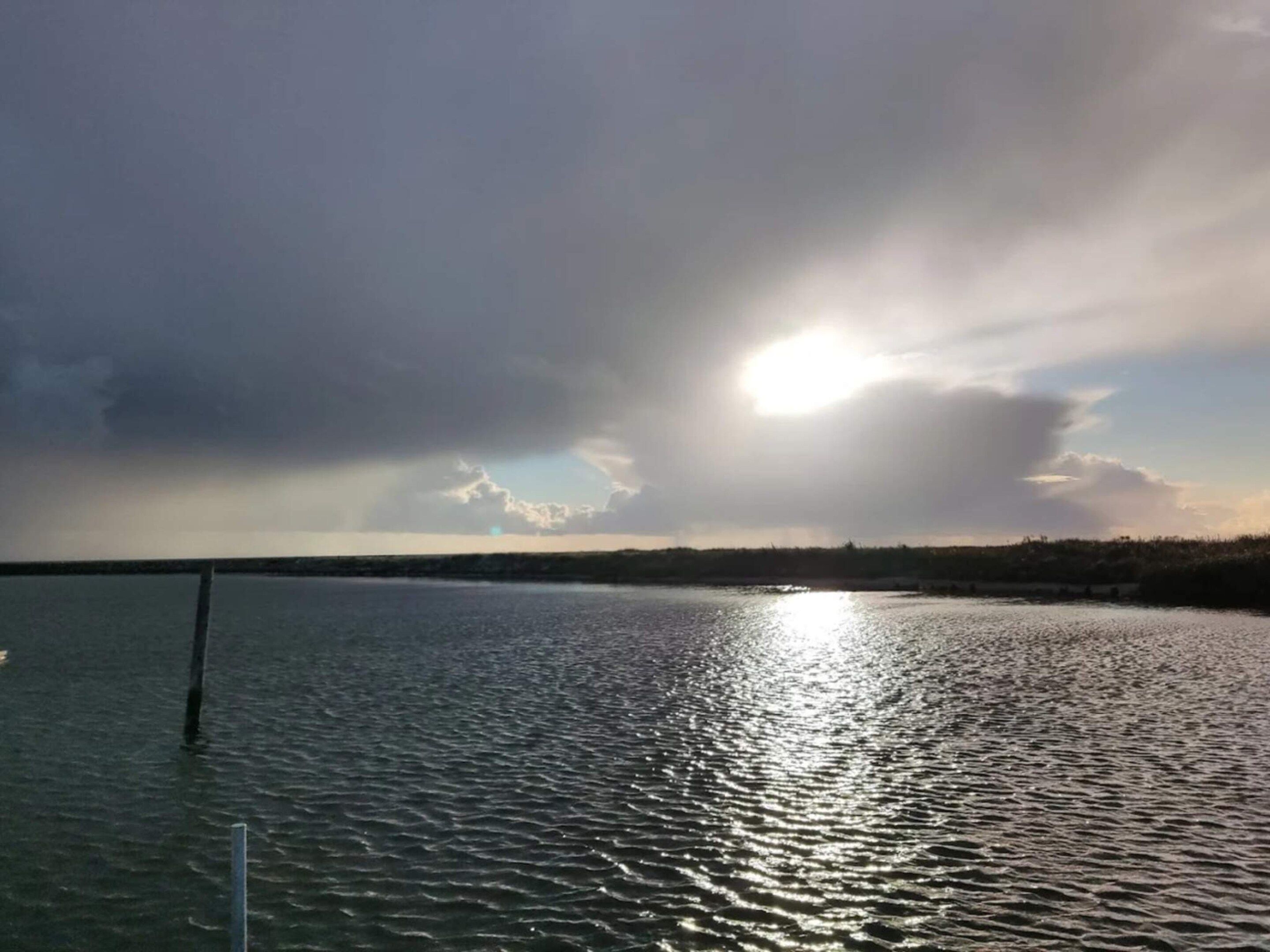 Stille vand med klar himmel og solskin gennem skyer.