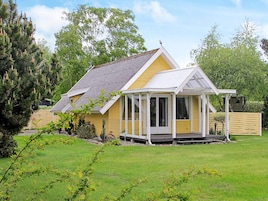 Una casa amarilla con porche cubierto y patio cercado.