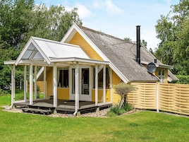 A yellow house with a covered porch and a chimney.