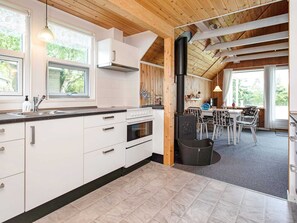Una cocina moderna con armarios blancos, una estufa y un amplio ventanal.