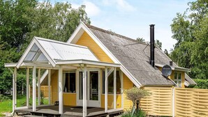 A yellow house with a covered porch, a chimney, and a satellite dish. - 4 Star Holiday Home in Dannemare (Dannemare)