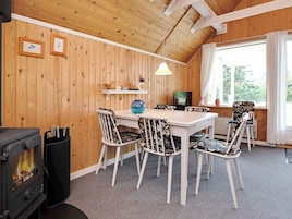 A cozy room with a wooden interior, a dining table with chairs, a fireplace, a television, and a window with curtains.
