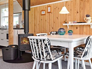 Una habitación acogedora con estufa de leña, muebles blancos y pared de madera.