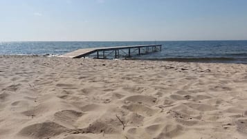 Una playa arenosa con un muelle de madera que se adentra en el agua.