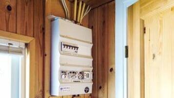 A utility meter with multiple dials and a control panel, mounted on a wall with wooden paneling.