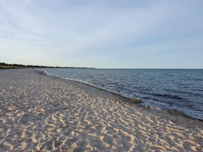 A sandy beach with gentle waves, a clear sky, and a distant shoreline. - Holiday Home in VÃ¦ggerlÃ¸se (Vaeggerlose)