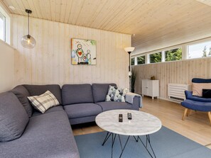 A modern living room with a sectional sofa, a round coffee table, and a painting on the wall. - Holiday Home in VÃ¦ggerlÃ¸se (Vaeggerlose)