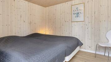 A bedroom with a bed, a chair, and a wall-mounted picture frame with text.