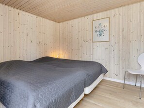 A bedroom with a bed, a chair, and a wall-mounted picture frame with text. - Holiday Home in VÃ¦ggerlÃ¸se (Vaeggerlose)