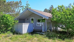 A small, single-story cabin with a gabled roof, a front porch, and a fenced yard.