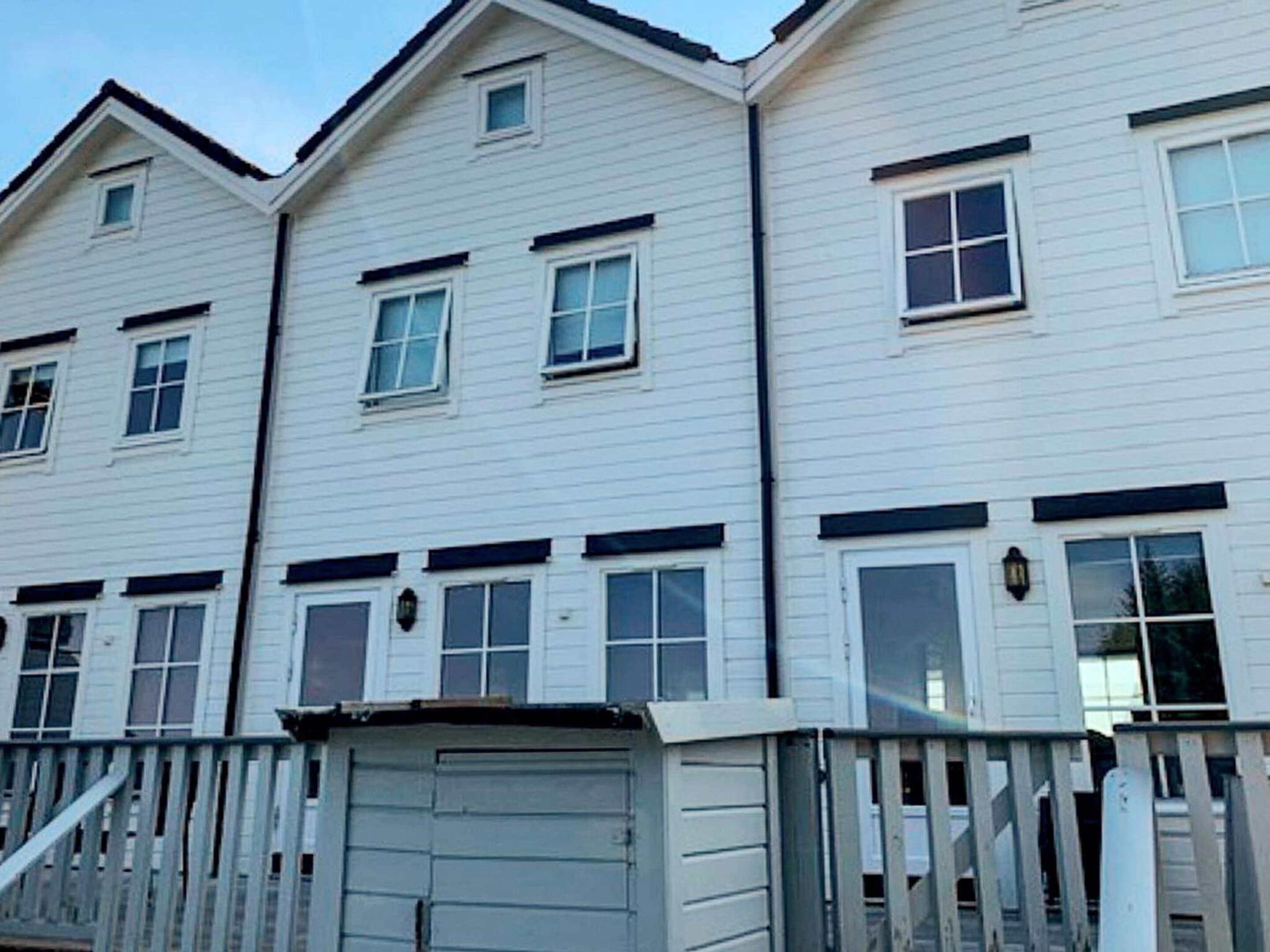 A row of white townhouses with multiple windows and a small garage.