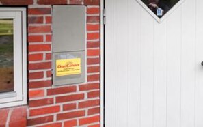 A brick wall with a sign that reads 'Dan Center' and a white door. - Holiday Home in NÃ¸rre Nebel (Norre Nebel)