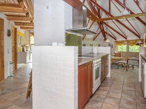A kitchen with a brick wall, wooden beams, and a tiled floor. - Holiday Home in NÃ¸rre Nebel (Norre Nebel)