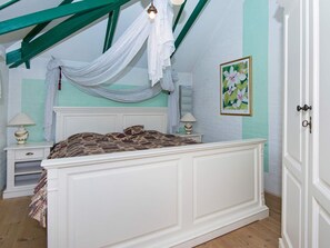 A bedroom with a bed, nightstands, a lamp, a painting, and a door. - Holiday Home in Nørre Nebel (Norre Nebel)