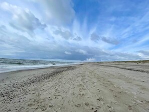 A beach with footprints leading to the water, a clear sky, and waves approaching the shore. - Holiday Home in NÃ¸rre Nebel (Norre Nebel)