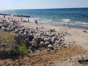 A beach with large rocks, people sunbathing, and the ocean in the background. - 6 Person Holiday Home in Gilleleje (Gilleleje)