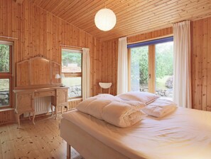 A wooden room with a bed, a desk, and a window.