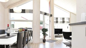 A modern dining area with a white table, black chairs, and a potted plant. - Holiday Home in GroÃŸenbrode (Grossenbrode)