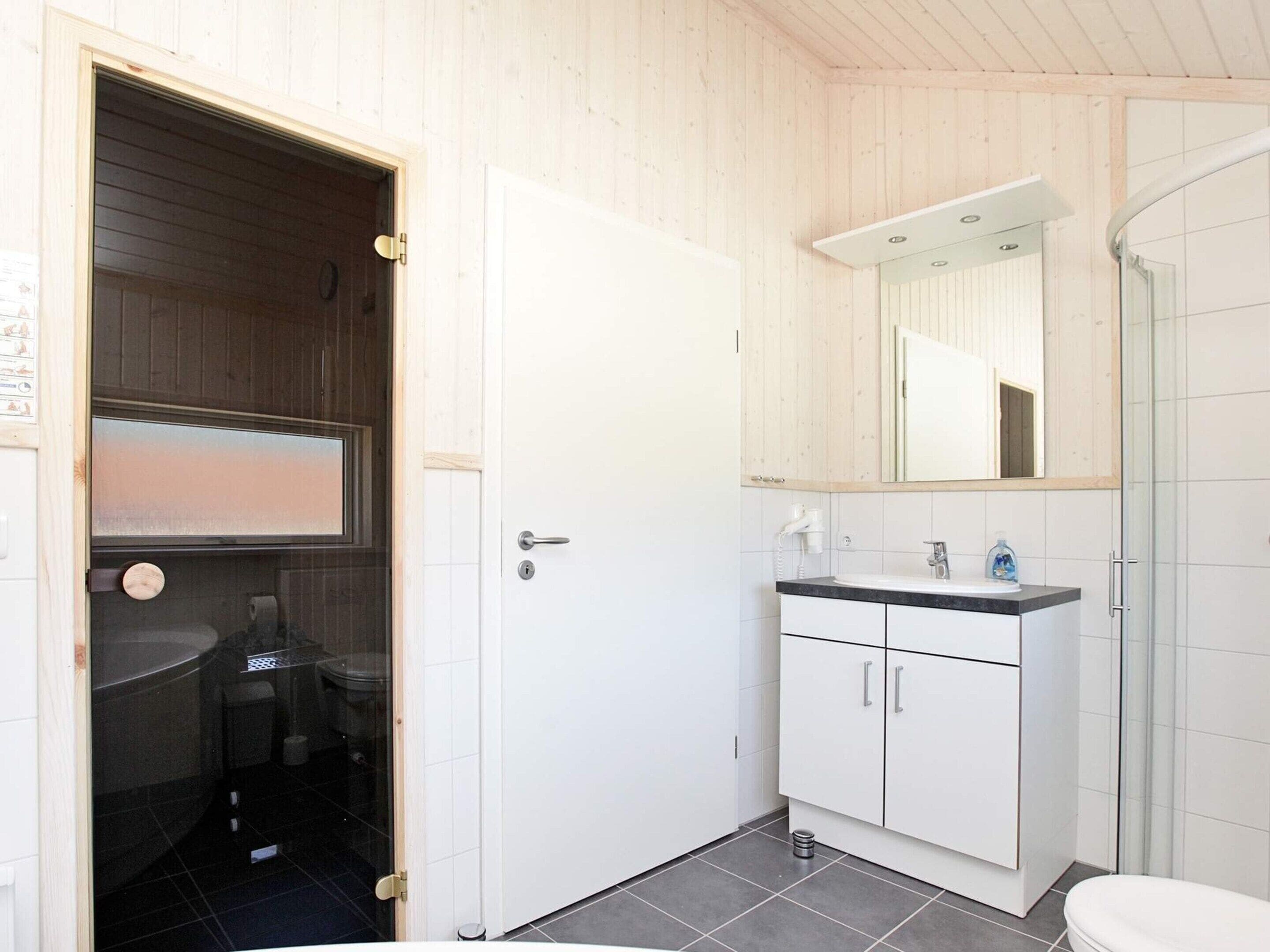 Un baño con inodoro, lavabo, espejo y ducha.