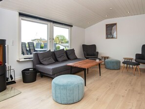 A modern living room with a grey sofa, a wooden coffee table, and a round ottoman.