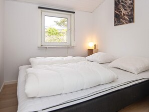 Quarto com cama, janela, luminária na parede e quadro emoldurado.