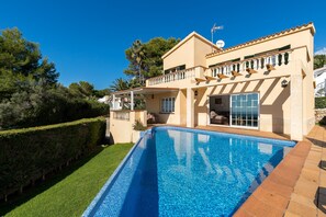 Una casa de dos pisos con piscina, balcón y una bandera.