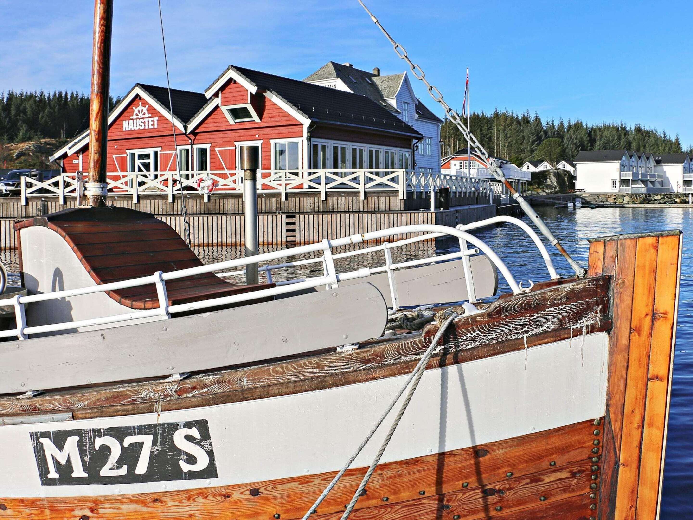 Un bateau était amarré à un quai, et on pouvait apercevoir en arrière-plan un bâtiment rouge sur lequel était inscrit le mot « NAUSTET ».