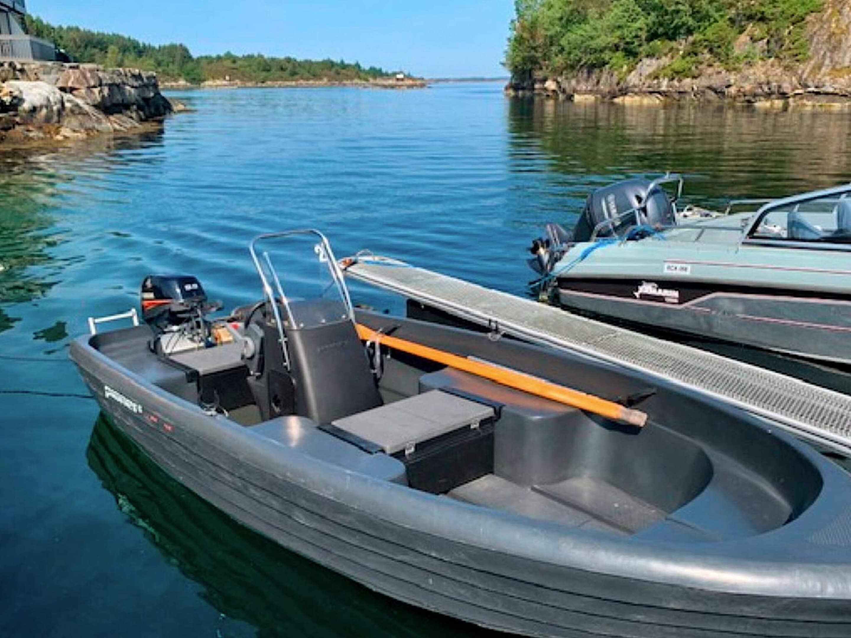 Een klein opblaasbaar bootje aangemeerd aan een steiger, met een motor en zitgedeelte.