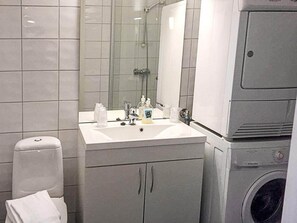 Une salle de bain avec un lavabo blanc, un miroir et un lave-linge.