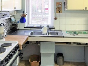 A kitchen with a stove, sink, and window.