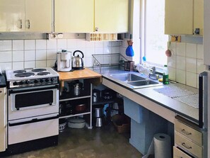 Cozinha com fogão, pia e diversos utensílios.