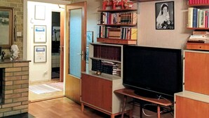 A living room with a television, bookshelves, a fireplace, and a door leading to another room. - 6 Person Holiday Home in Rorbacksnas (Lima)