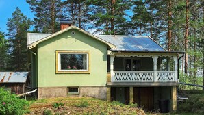A two-story house with a green exterior, a balcony with decorative railings, and a metal roof. - 6 Person Holiday Home in Rorbacksnas (Lima)