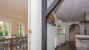 Una cuina àmplia amb un disseny modern, una zona de menjador amb mobles de fusta i una escala que condueix a un nivell superior.