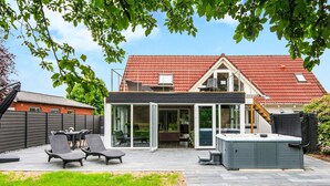 A modern house with a patio, outdoor seating, and a hot tub. - 8 Person Holiday Home in Henne (Henne)