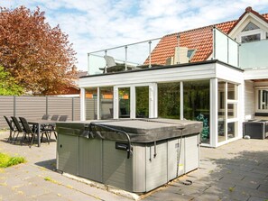 A modern house with a glass conservatory, a hot tub, and a patio with outdoor furniture. - 8 Person Holiday Home in Henne (Henne)