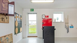 A room with a white wall, a door with a green exit sign, a red fire extinguisher, and a window with a view of greenery. - 8 Person Holiday Home in Henne (Henne)