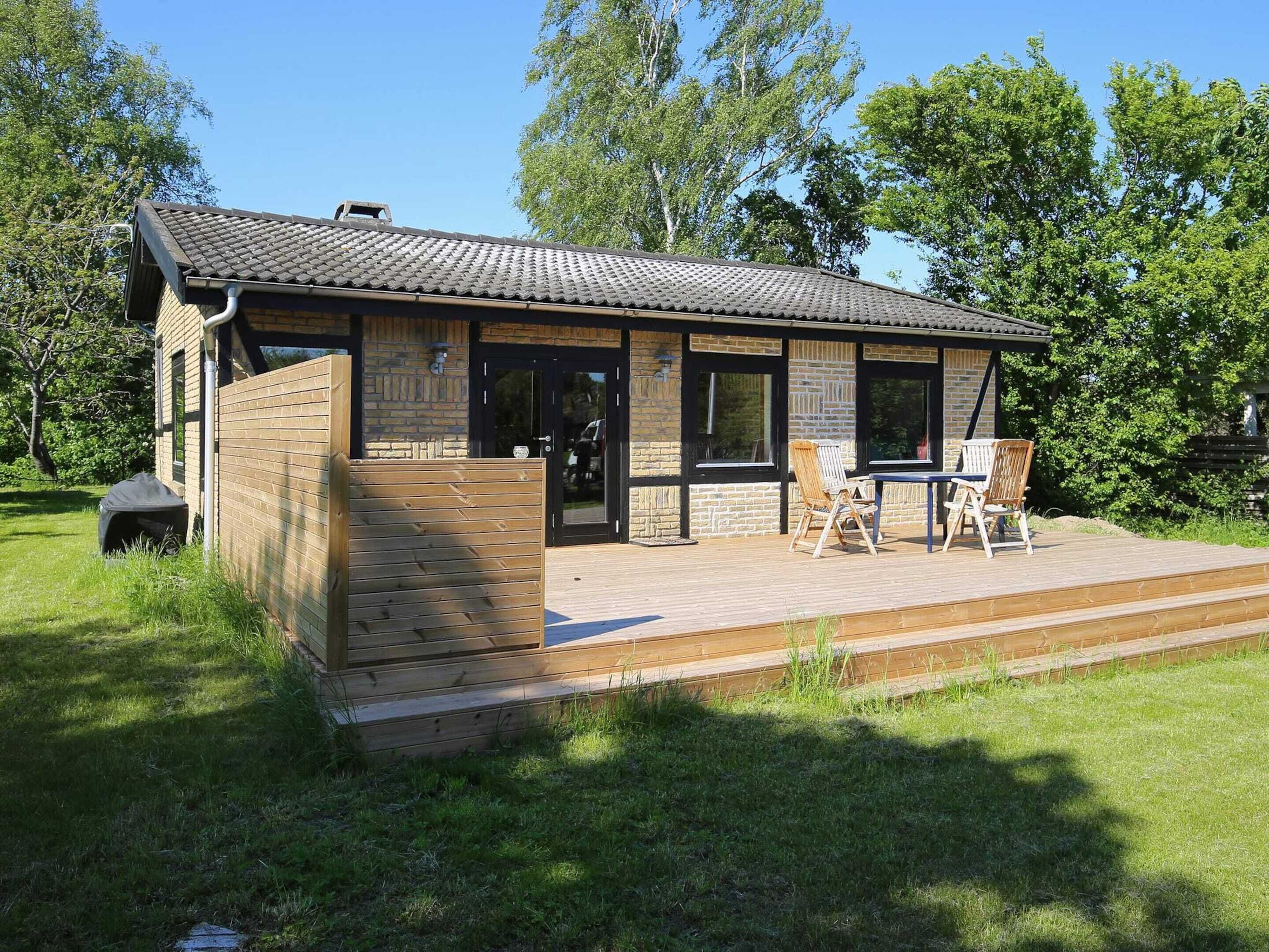 Een houten chalet met een pannendak, een terras met tuinmeubilair en een gevel van baksteen.