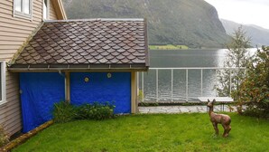 Ett hus med en blå garageport, ett staket av metall och en staty av en lama på gården.