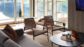A room with a view of a lake and mountains, furnished with wicker chairs, a sofa, and a small table with a plant and candle. - 8 Person Holiday Home in Skei i Jolster (Sunnfjord)