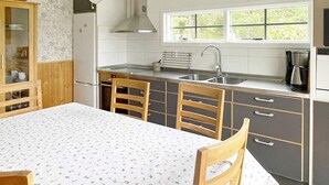 A kitchen with a dining table, chairs, a window, and a sink.