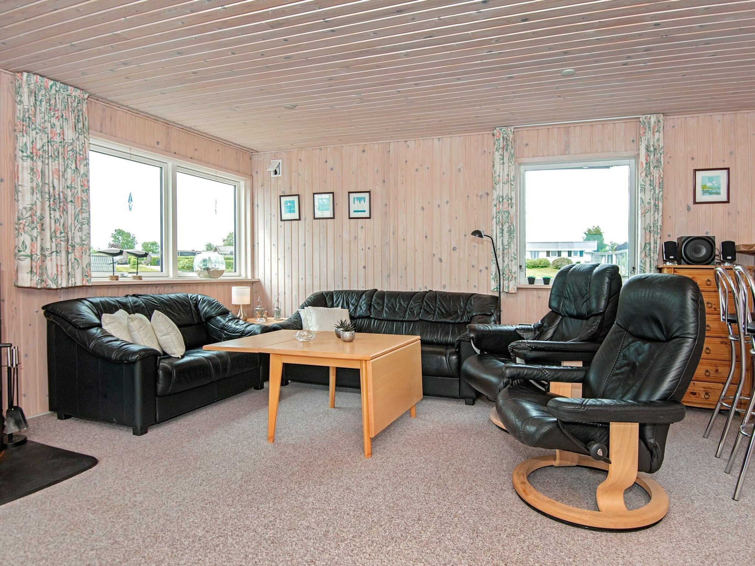 A room with a black leather sofa, a wooden coffee table, a black leather recliner, and a wooden cabinet.