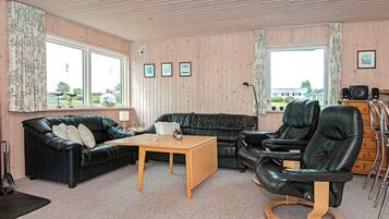 A room with a black leather sofa, a wooden coffee table, a black leather recliner, and a wooden cabinet.