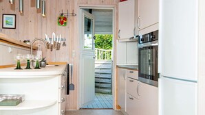 A kitchen with white cabinets, a stainless steel oven, and a door leading to a balcony. - 5 Person Holiday Home in Hejls (Hejls)